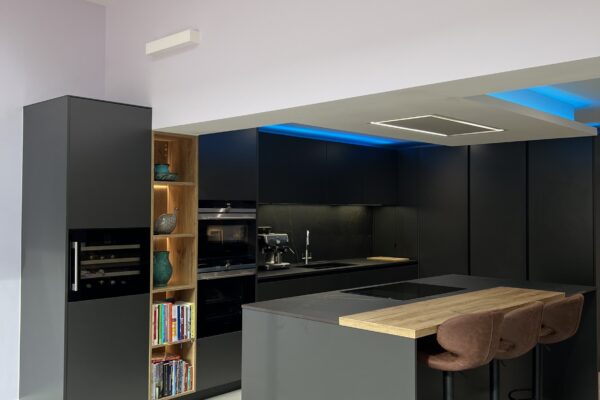 Loughton kitchen with Caneo dark graphite cabinetry, natural oak island and open illuminated shelving